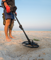 Mand med metaldetektor på strand